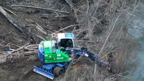 River pollution: excavator at work to remove broken oil tank - telephoto 7x Video stock 231126028