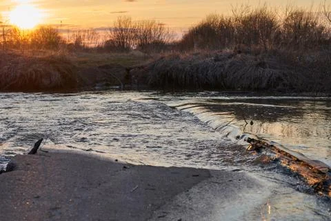 River with a rapid flow in the spring at sunset Stock Photos