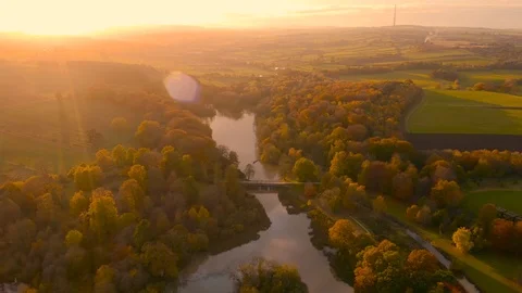 River reflecting sunset over rural English countryside - Aerial footage, Autumn Stock Footage 119580942
