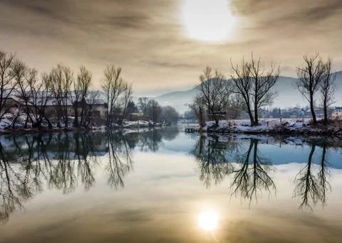 River reflection of trees and a yellow sun Stock Photos