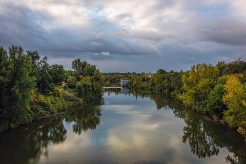 River with reflections of green trees under blue skies with fluf Stock Photos