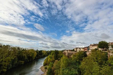 River with reflections of green trees under blue skies with fluf Stock Photos