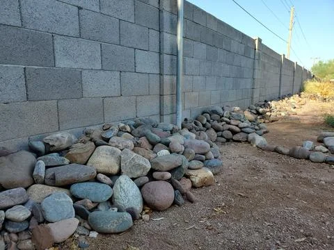 River Rocks Piled Up Against A Cinder Block Wall in Arizona Backyard Stock Photos