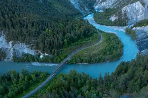A river that runs in a S curve between the mountains,a railroad bridge cros.. 写真素材