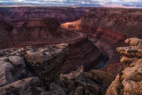 A river runs through an eroded out canyon near a mountain 스톡 사진