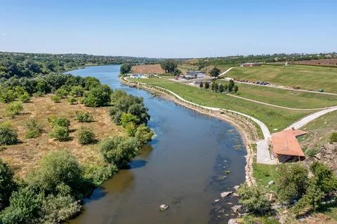 A river runs through a landscape filled with trees and open fields. People ca Stock-Fotos