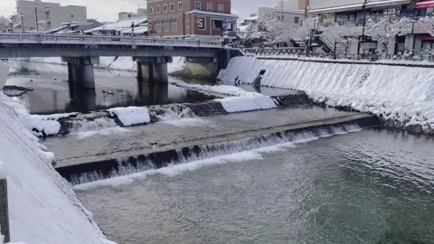 A river in a rural town in winter flows through the snow-covered city banks. Stock Footage 304846865