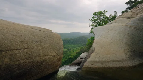 River rushes to waterfall edge, framed by large rocks. Dynamic dolly shot over Stock Footage 273971030