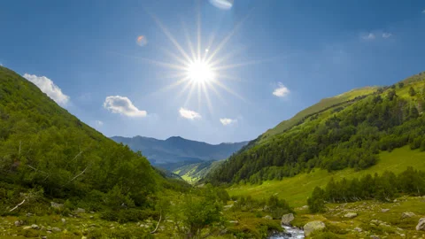 River rushing through green mountain valley at sunny day time lapse scene Stock Footage 197484961