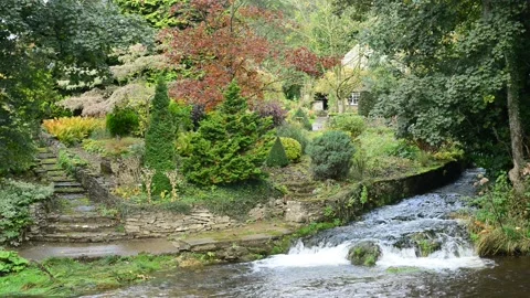 River rye flowing over waterfall by cottage at Rievaulx Abbey UK Stock Footage 158757878