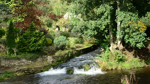 River rye flowing over waterfall by cottage at Rievaulx Abbey UK Stock Footage 158758109