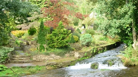 River rye flowing over waterfall by cottage at Rievaulx Abbey Yorkshire Moors UK Stock Footage 163519587