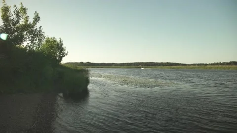 A river scene in green summer meadows and a motor boat passing by Stock Footage 161153435