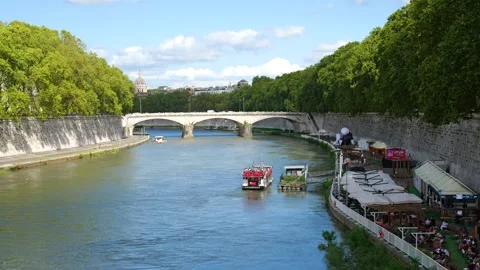 River scene rome busy bridge above it traffic boats docked along riverbanks 스톡 동영상 320843477
