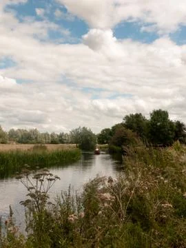 River side scene outside with row boat in distance of country Stock Photos