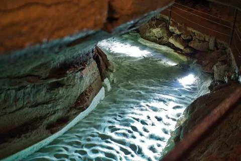 A river in a stalactite cave is going trough Stock Photos