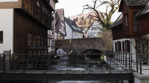 A river, stone bridge and walking people in the foreground, houses are in the Stock Footage 120522257