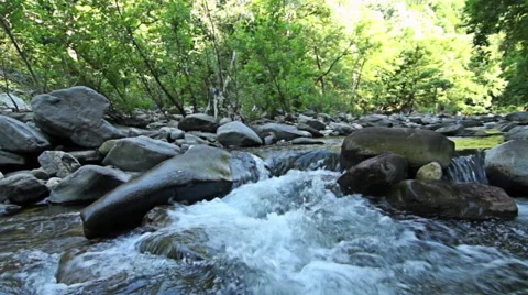 A river stream flows over rocks in this beautiful mountains scene Stock-Footage 52628299