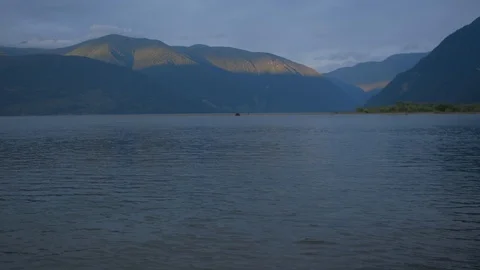 River at sunset against the background of mountains. boat floats in the distance Stock Footage 125826948
