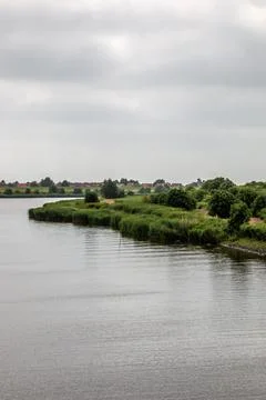 River throught green fields of grass in the middle of the countryside Stockfoto's