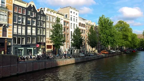 A river in a traditionally looking town, buildings and trees in a street and the Stock-Footage 73958700