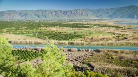 River valley covered by green fields with zoom to tractor. 4k Stock Footage 61767533
