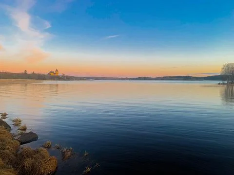 The river is visible against the background of the setting sun, a peach sky with Stock Photos