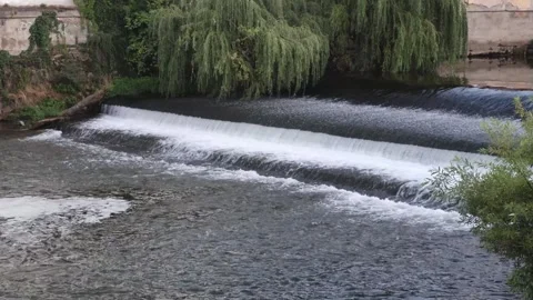 River water cascading over a low weir beneath overhanging willow branches, .. Stock-Footage 348193469