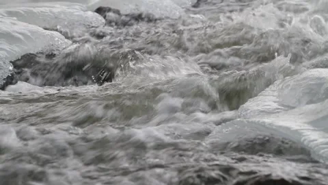 River water flows rapidly and violently between the ice Stock Footage 148129350