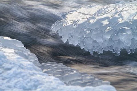River water flows rapidly between the ice of a bizarre shape Stock Photos