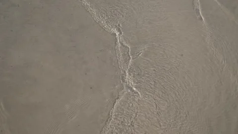 River waves gently lapping on sandy beach. Calm water and sand texture. Stock Footage 312956400