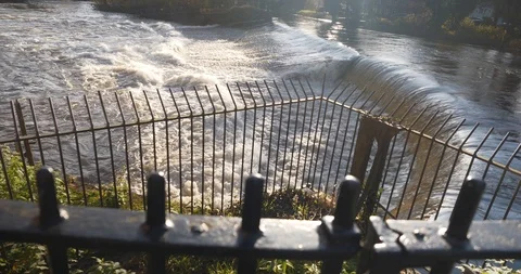 River weir in sunny haze with metal raings in foreground focus pull Stock Footage