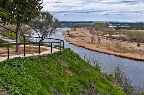River winding through marshland with path on hillside Stock Photos