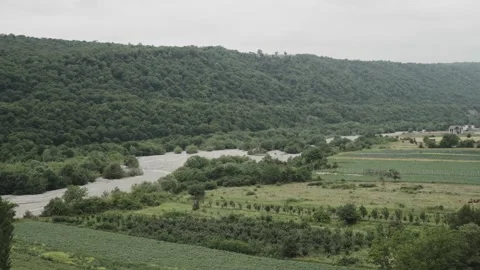 A river winds beside cultivated fields and forested hills near Shahdag under an Stock Footage 345258914