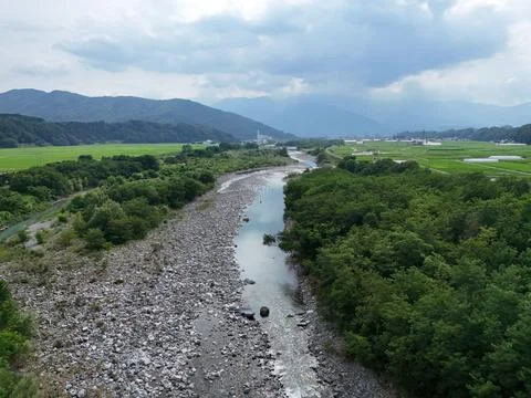 River winds through rocky bed, flanked by lush greenery Stock Photos