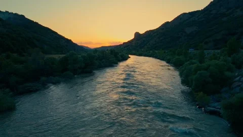 River winds through rocky terrain as sun dips below horizon 스톡 동영상 332366351