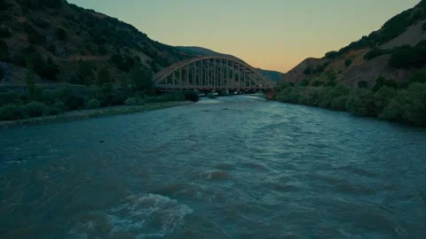 River winds through rocky terrain as sun dips below horizon 스톡 동영상 332366806