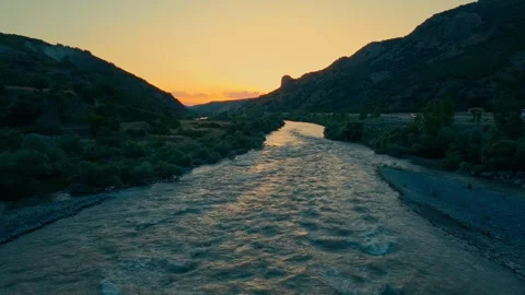 River winds through rocky terrain as sun dips below horizon 스톡 동영상 332367169