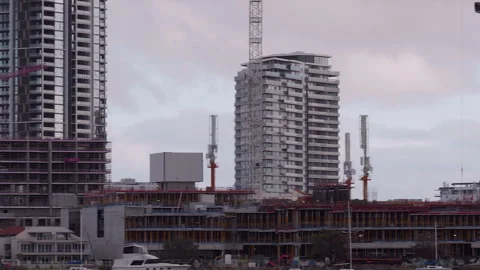 Riverside building constructions &amp; cranes plus skyscrapers framed by cloudy sky  Video stock 252054096