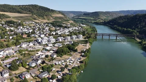 Riverside homes line a broad river beneath cultivated hills 動画素材 342336112