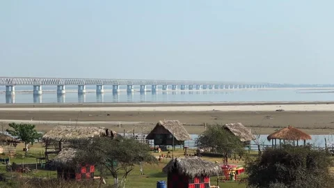 Riverside huts with long bridge in background Stock Footage 331277617