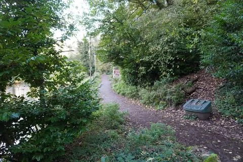 Riverside Path With Trees, Lights, And Green Bin In Matlock Bath, England Stock Photos