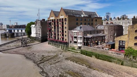 Riverside pubs and converted warehouse buildings crowd the water's edge above Stock Footage 343467332
