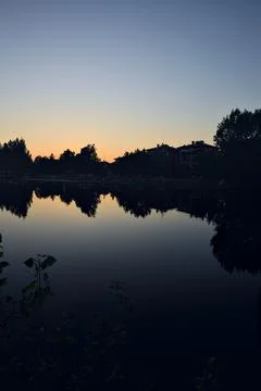 Riverside  at sunset with its reflection casted in the water at sunset seen.. Stock Photos