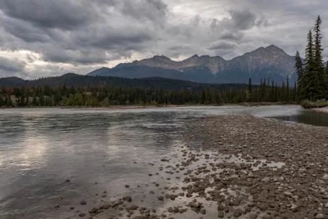 A riverside view down the river at sunset of the Athabasca River as it weaves Stock Photos