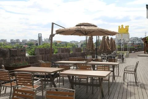 Riverside wooden deck with empty tables and straw umbrellas under bright cl.. Foto stock
