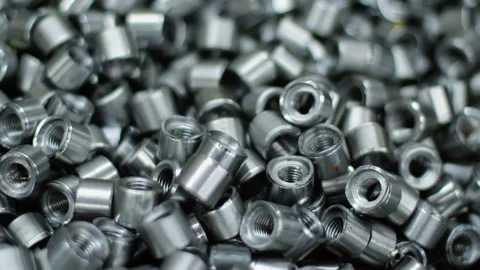 Rivet nuts pile closeup, focus pull. Shiny threaded steel fasteners factory. Stock Footage 345680218