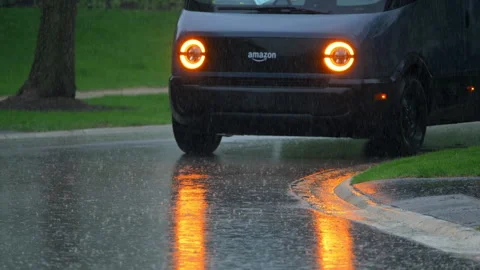 Rivian electric delivery Amazon van delivery parcel through heavy rain in Stock Footage 335951475