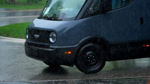 Rivian electric delivery Amazon van driving through heavy rain in suburban 스톡 동영상 335951617