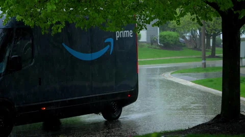 Rivian electric delivery Amazon van driving through heavy rain in suburban Stock Footage 335951677